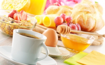 Frühstücksgedeck mit Brötchen, Kaffee, Ei, Honig, Müsli